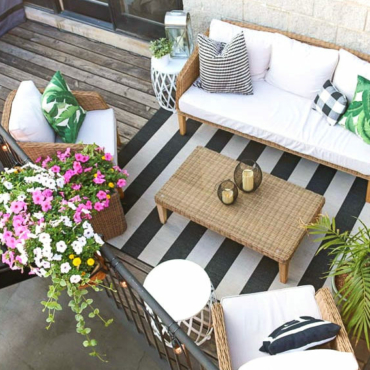 a top-down view of a small balcony with furniture, rigs and overflowing flowers
