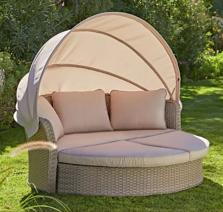 Rattan day bed with canopy and neutral coloured cushions