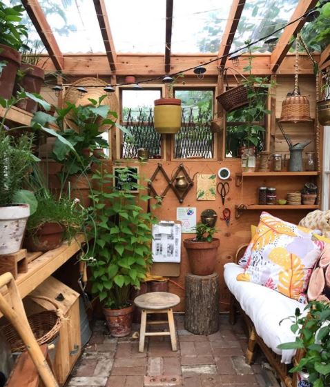 a busy potting shed, filled with plants, a work bench and a cosy sofa