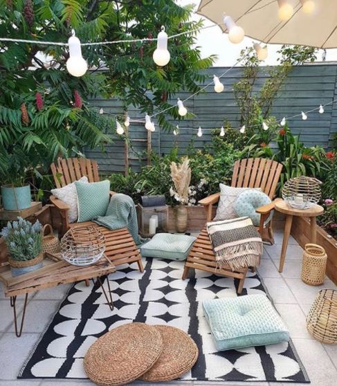a cosy patio with seating and cushions with string lights zig-zagging across