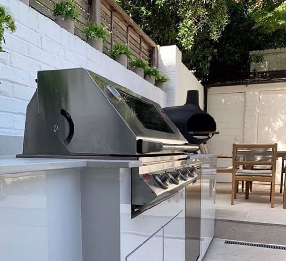 8 Garden BBQ Area Ideas for Stylish Outdoor Grilling 1 a modern outdoor kitchen with a stainless steel in-built BBQ grill