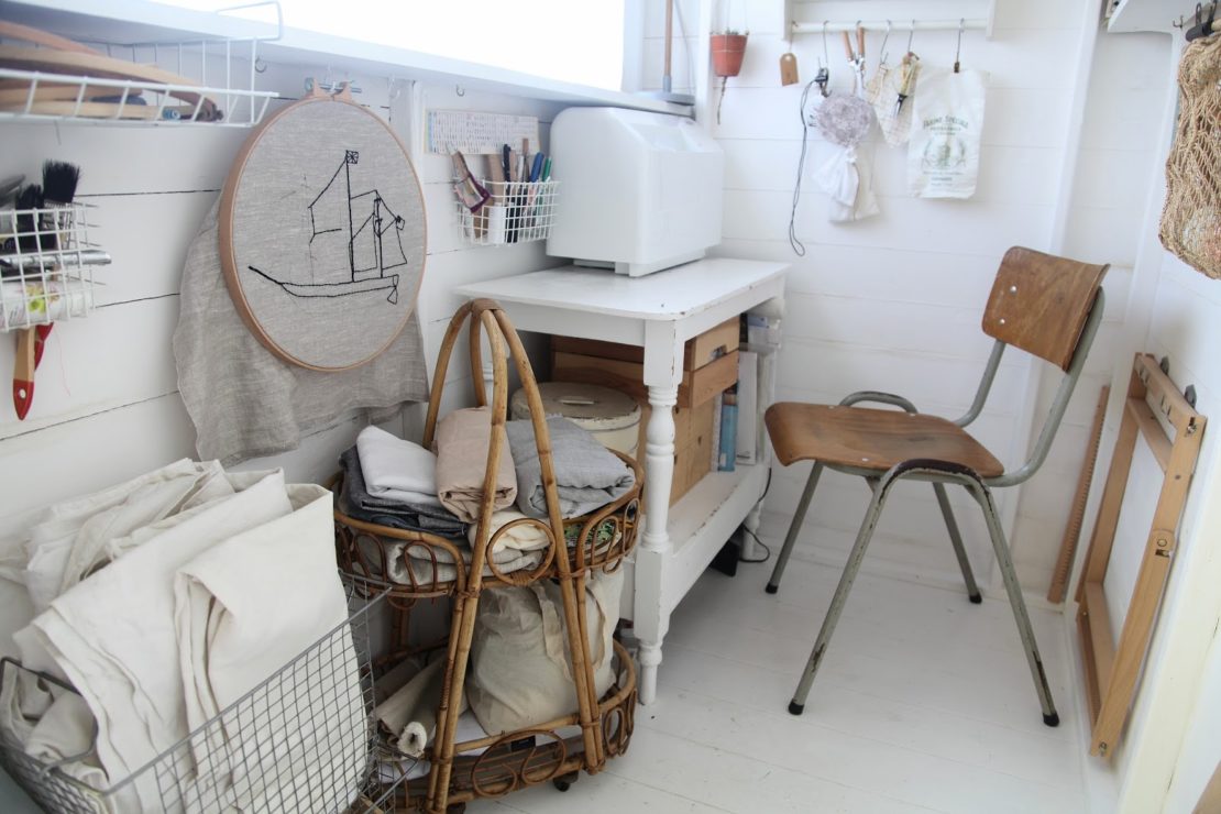 a narrow shed filled with sewing paraphernalia, including a cross stitch hoop and squares of fabric