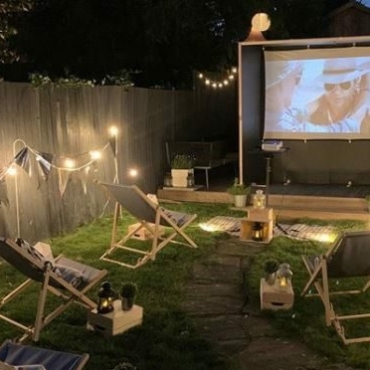 a night-time cinema set up with deck chairs and string lighting