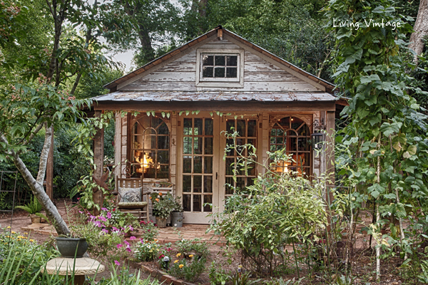 a rustic, weathered wooden shed with large windows and a covered porch