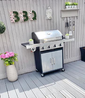 a sleek freestanding BBQ on a grey deck with pretty garden decorations