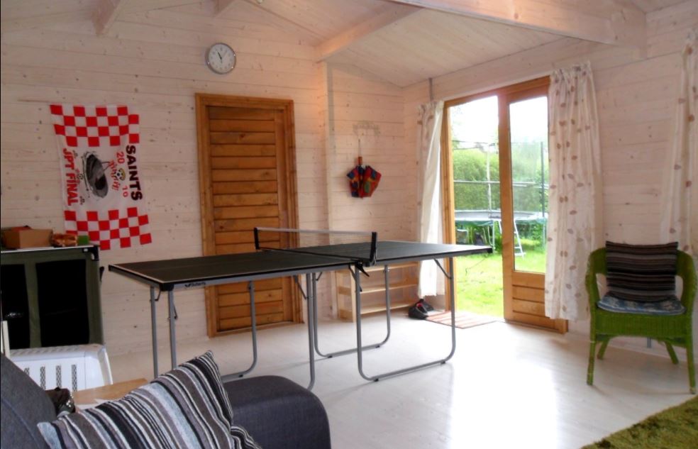 a spacious garden shed with a ping pong table in the middle