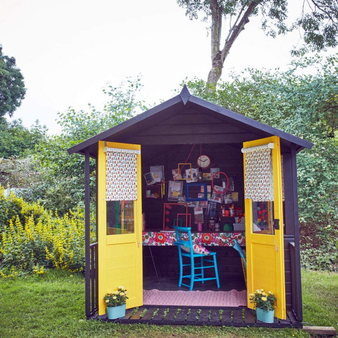 a wooden cabin with door painted bright yellow and an artistic collection of pictures and frames on the wall