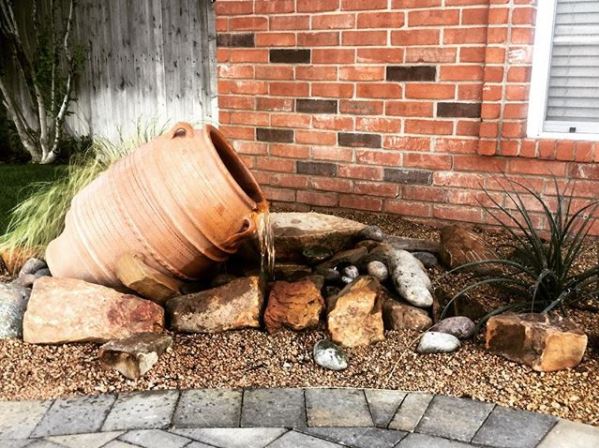 garden water feature ideas using a clay pot amphora fountain on its side, pouring into gravel