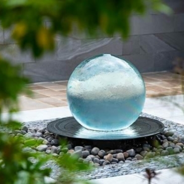 a spherical garden fountain with water gently flowing over it