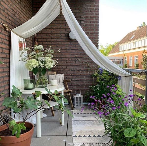 a curtain draped from the roof of a balcony, over the railings to create privacy and shade