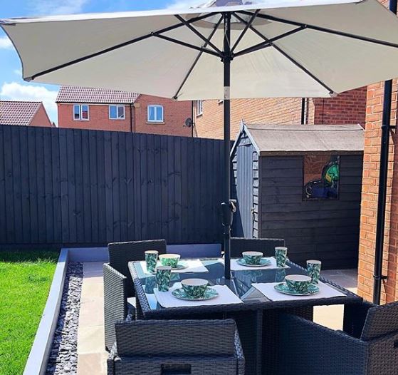a dark grey shed painted to blend in with a dark grey garden fence