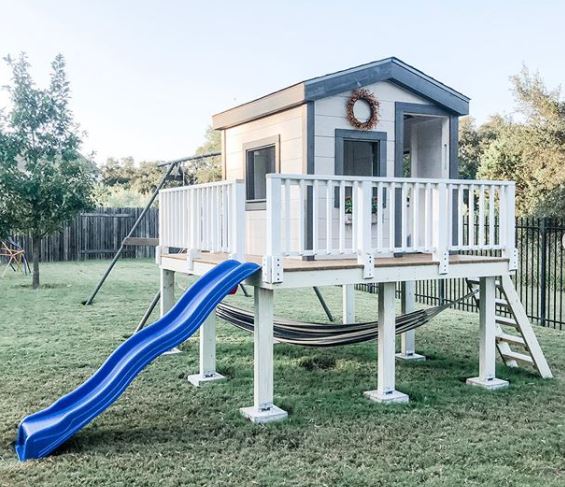 a shed on a raised platform, with a ladder and slide