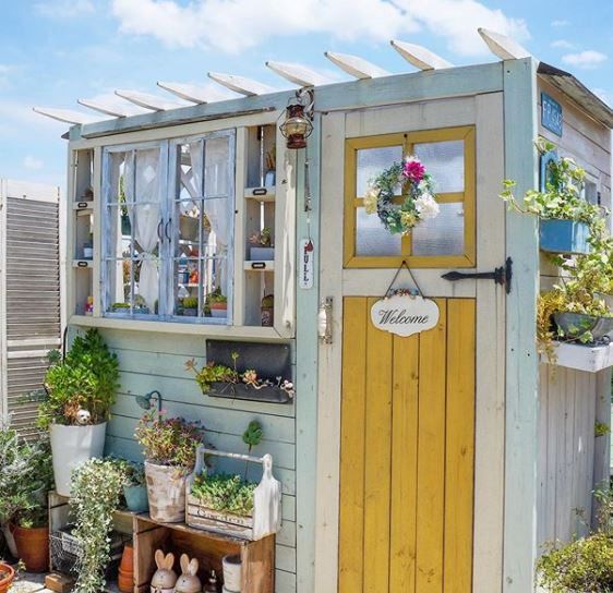 a pale blue beachy shed with a sunny yellow door