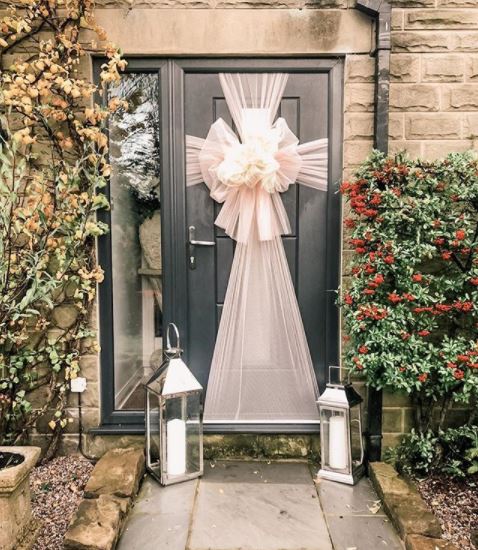 A dark grey door with a shimmery cream bow wrapped around it, like a gift