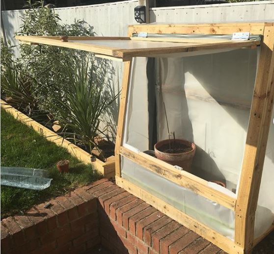 a mini greenhouse made from recycling wooden pallets