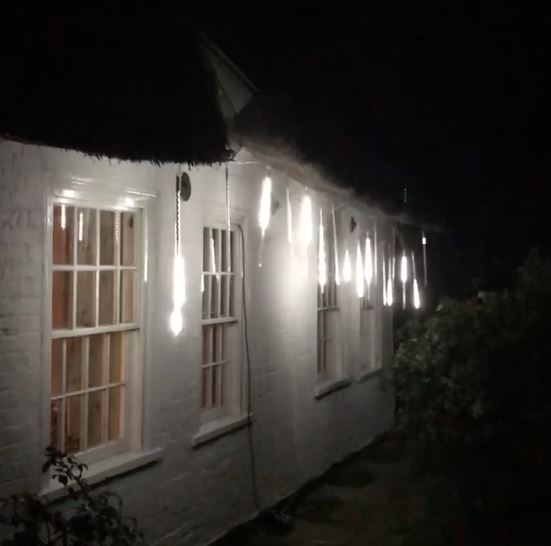 meteor lights hanging from the outside of a thatched cottage