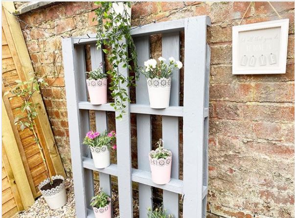 DIY garden pallet ideas using paint and leaning the pallet against the wall to use it as a shelf