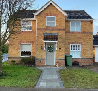 a large new-build home with a trim lawn and tidy garden path